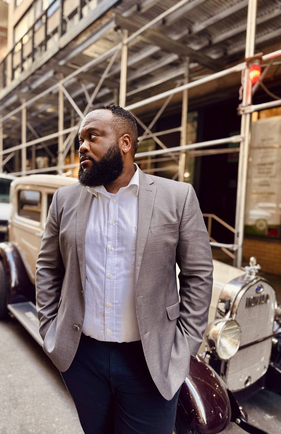 Shane S. Scott standing beside a vintage car on a New York City street